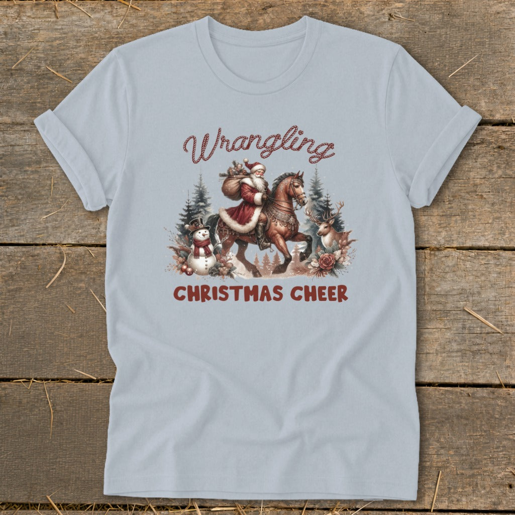 Light blue t-shirt with Santa riding a horse and the text "Wrangling Christmas Cheer."