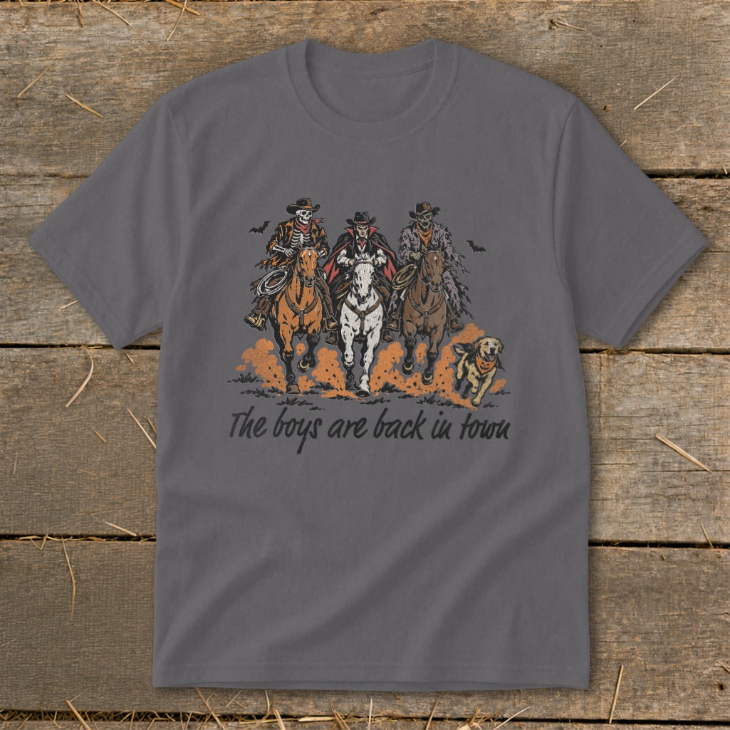 Skeleton cowboys and a vampire ride horses with a dog under the text "The boys are back in town."