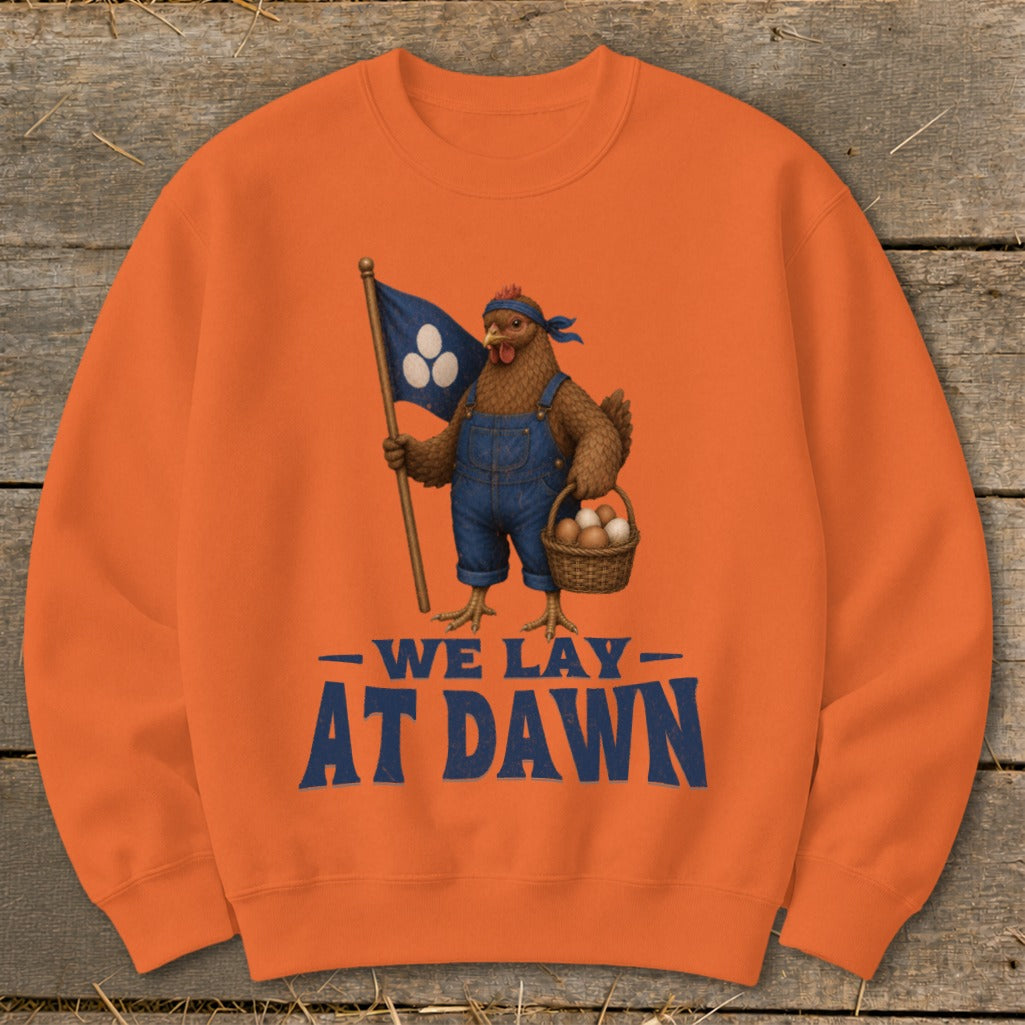 Orange sweatshirt with chicken in overalls holding flag and egg basket, text reads "We Lay At Dawn".