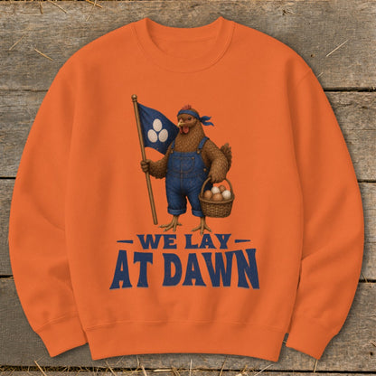 Orange sweatshirt with chicken in overalls holding flag and egg basket, text reads "We Lay At Dawn".