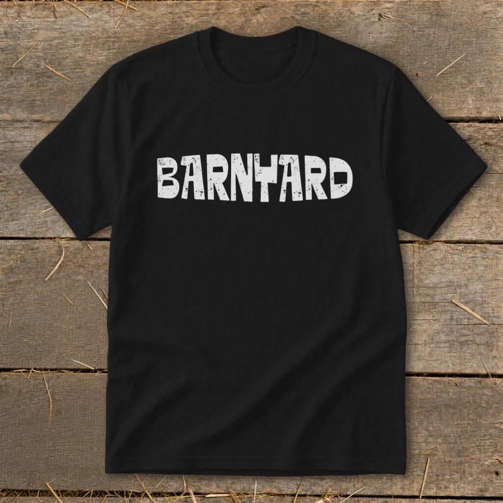Black short-sleeve t-shirt with the distressed white text BARNYARD centered on the chest, laid flat on a rustic wooden surface.
