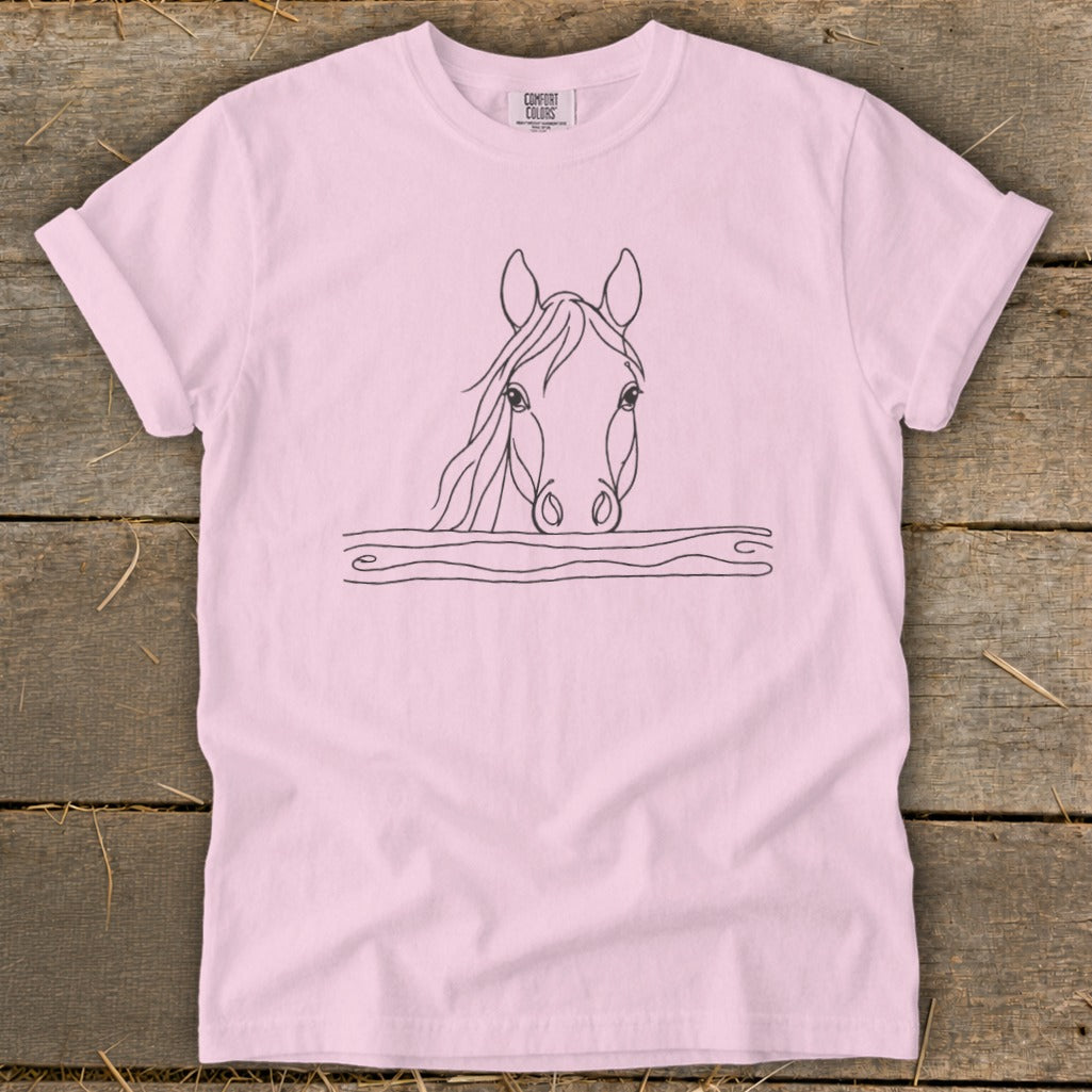 Pink t-shirt with a minimalist black line drawing of a horse's head above a wooden fence.