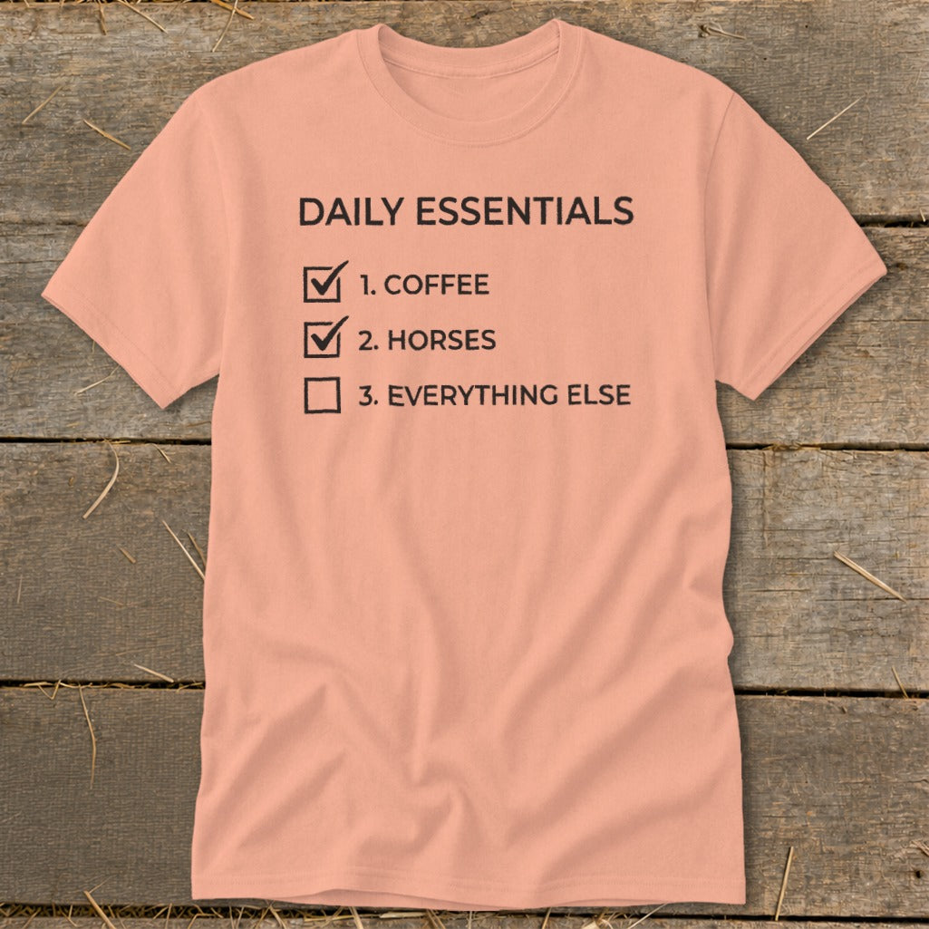 Peach t-shirt with "Daily Essentials" checklist: coffee, horses, everything else.