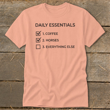 Peach t-shirt with "Daily Essentials" checklist: coffee, horses, everything else.