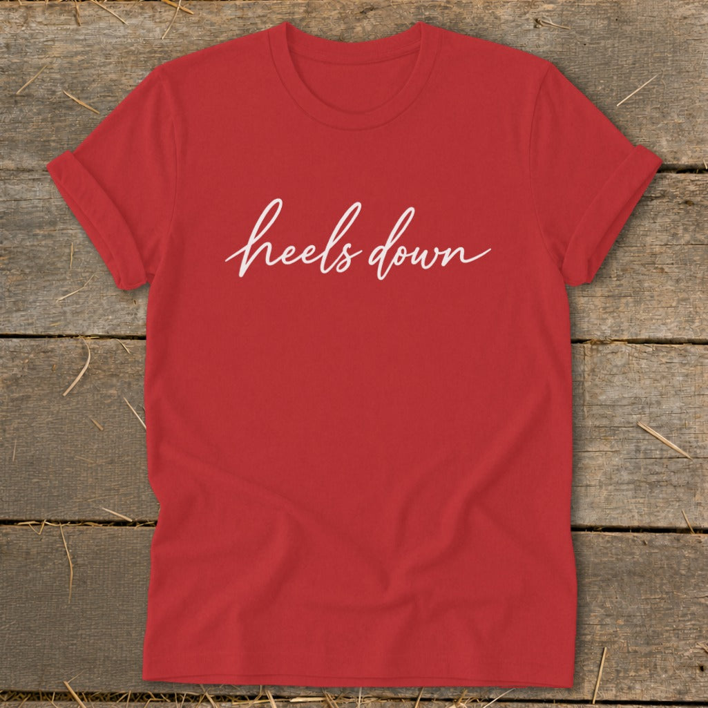 Red t-shirt with white cursive text that reads "heels down."