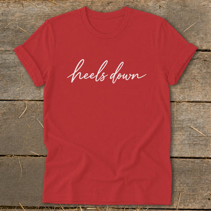 Red t-shirt with white cursive text that reads "heels down."