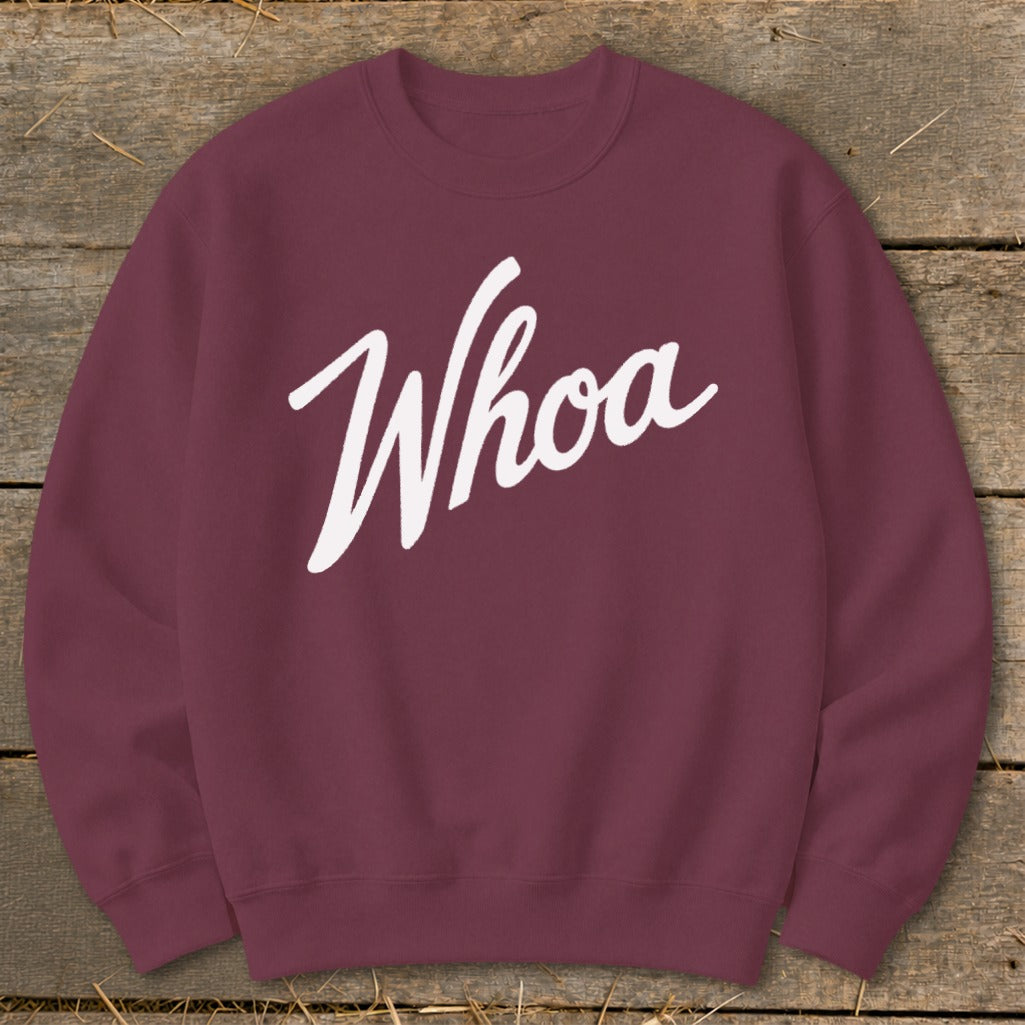 Maroon sweatshirt with white script text reading "Whoa" on a wooden background.