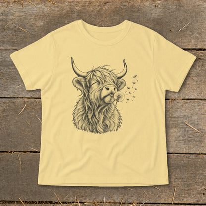 Yellow t-shirt with a sketch of a Highland cow blowing dandelion seeds.