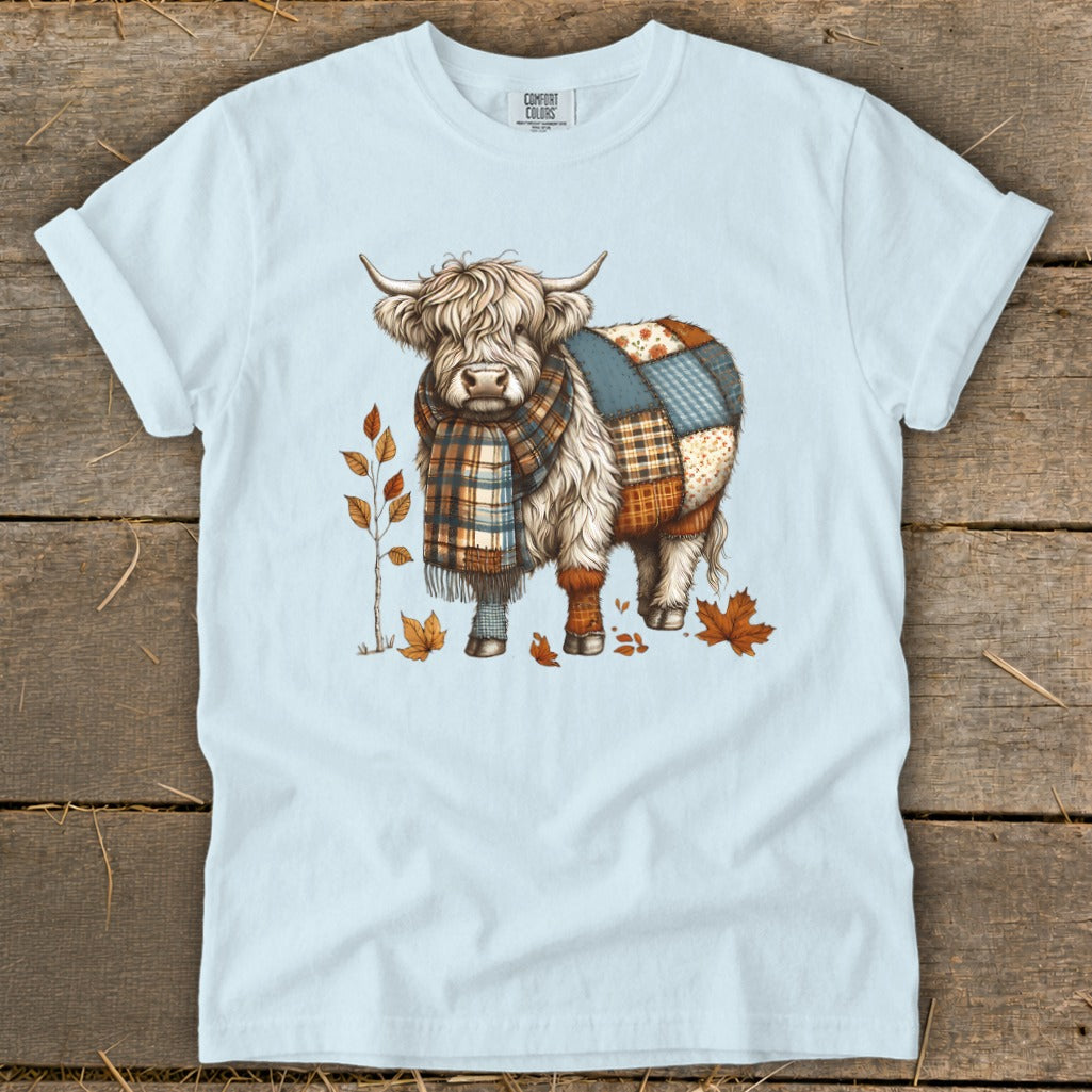 Light blue t-shirt with a patchwork Highland cow wearing a scarf.