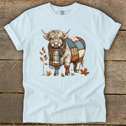 Light blue t-shirt with a patchwork Highland cow wearing a scarf.