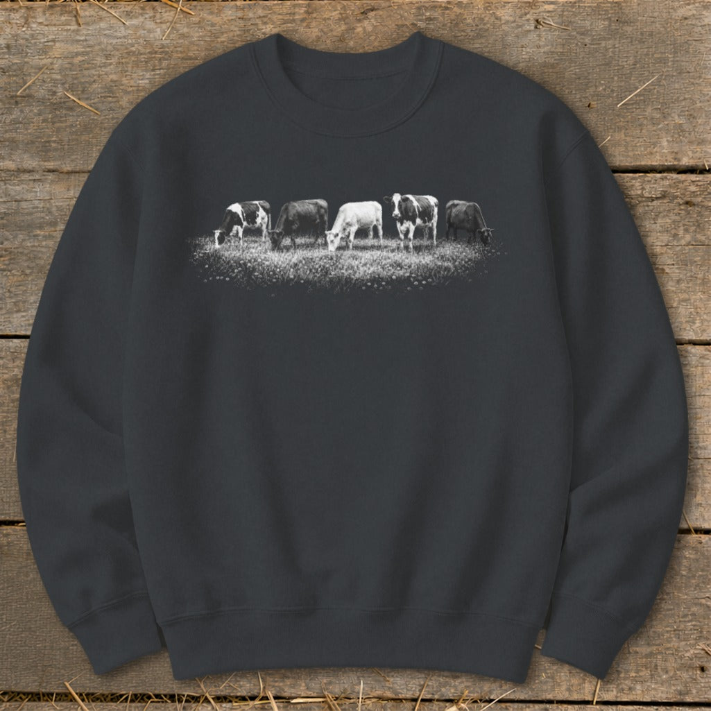 Sweatshirt with a graphic of five cows grazing in a field of wildflowers.