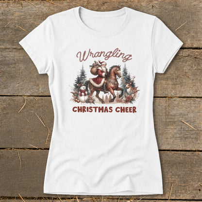 White t-shirt with "Wrangling Christmas Cheer" text and a watercolor illustration of Santa on horseback.