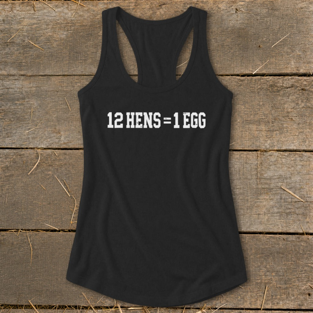 Black women's racerback tank top featuring the white text 12 HENS = 1 EGG on a wooden background.
