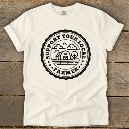 Cream t-shirt with black circular logo featuring barn, tree, and "Support Your Local Farmer" text.