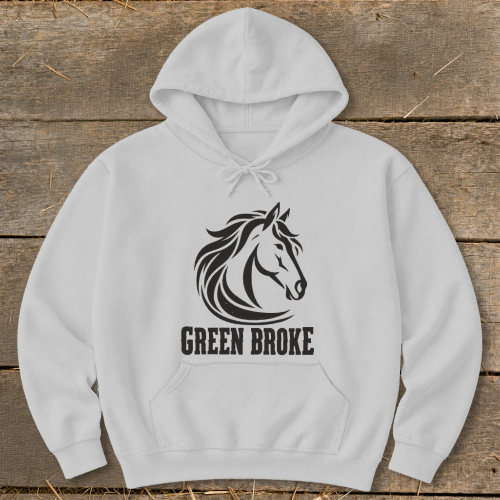 A light gray hooded sweatshirt with a black horse graphic and the text "GREEN BROKE" on a wooden background.