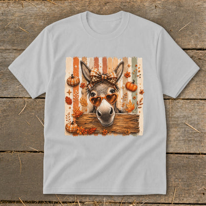 Donkey wearing bow and heart sunglasses among pumpkins and fall leaves.