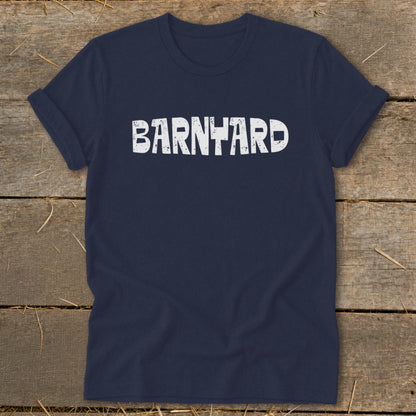 Navy blue crew neck t-shirt with distressed white text reading BARNYARD laid on a wooden surface.