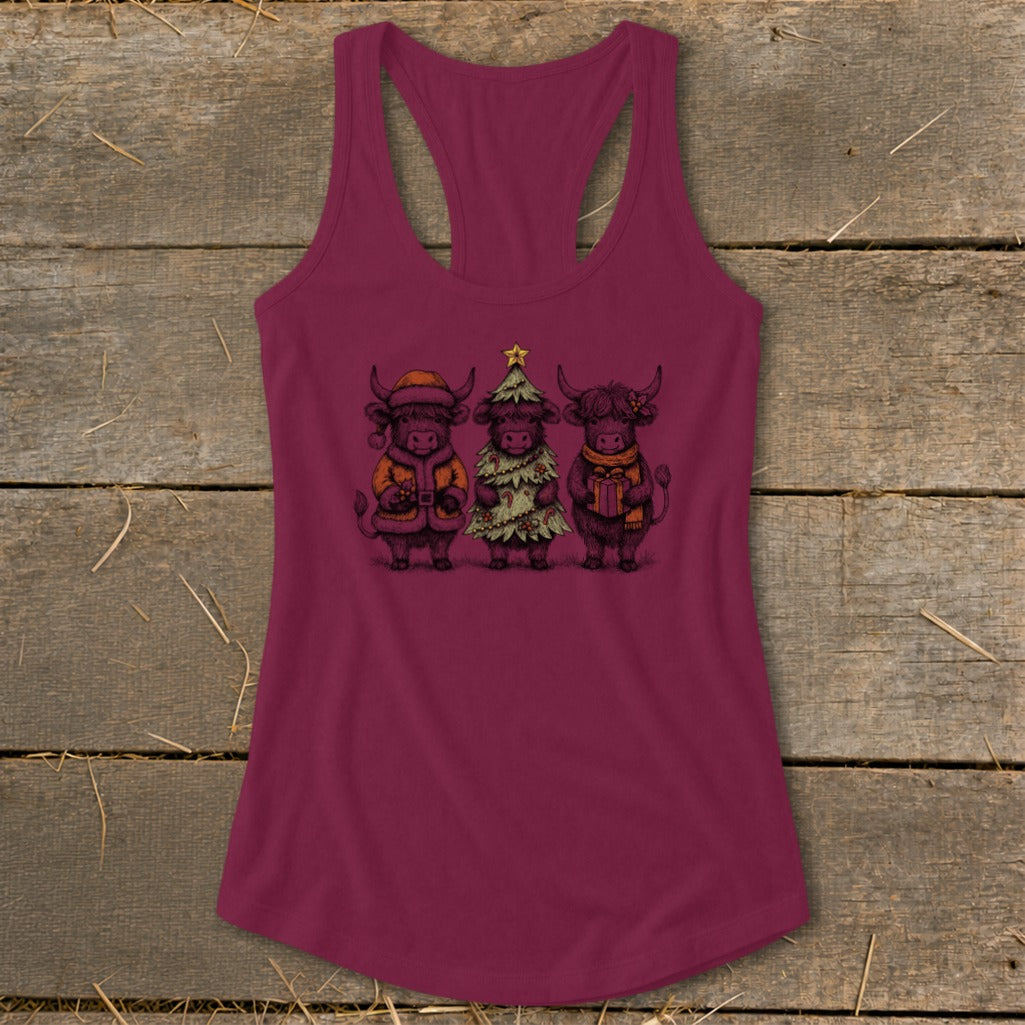 Three highland cows dressed for Christmas, one as a tree, on a maroon tank top.