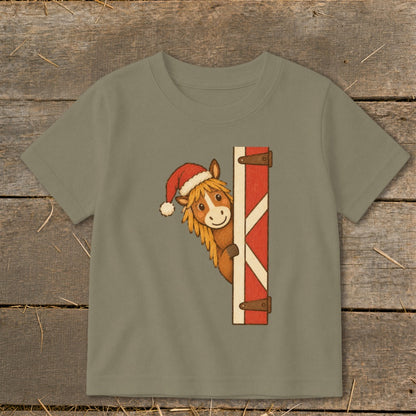 T-shirt with a cartoon horse wearing a Santa hat peeking from behind a barn door.