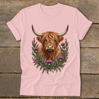 Highland cow portrait surrounded by thistles on a pink t-shirt.