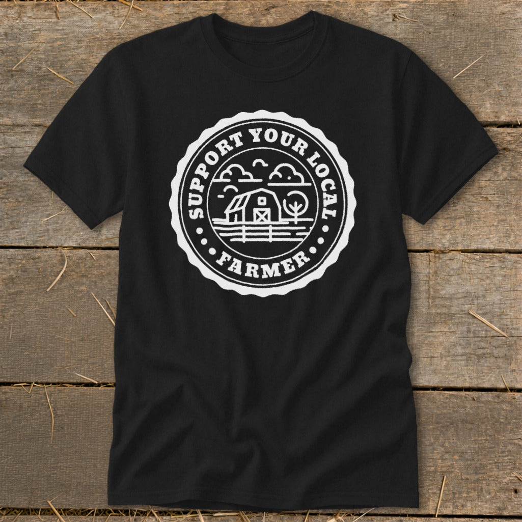 Black t-shirt with circular white design featuring a barn, clouds, and text "SUPPORT YOUR LOCAL FARMER".