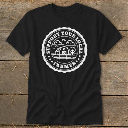 Black t-shirt with circular white design featuring a barn, clouds, and text "SUPPORT YOUR LOCAL FARMER".