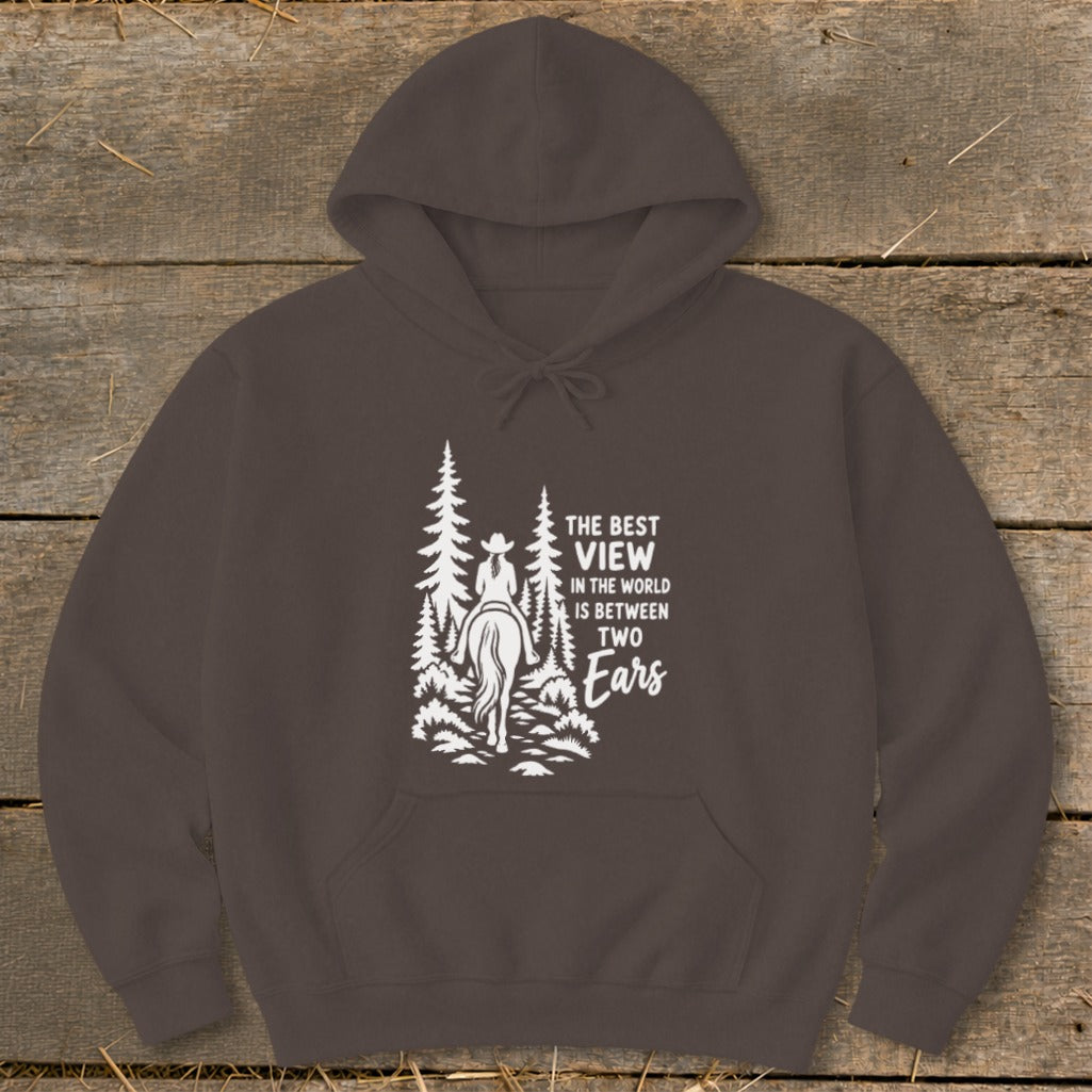 Dark brown hoodie featuring a white graphic of a person on horseback amidst trees with text reading The best view in the world is between two ears.
