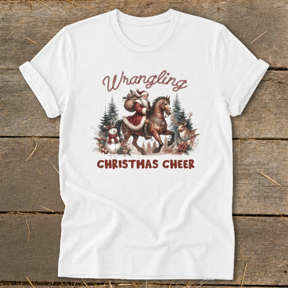 White t-shirt with "Wrangling Christmas Cheer" text and Santa on horseback with snowman and reindeer.