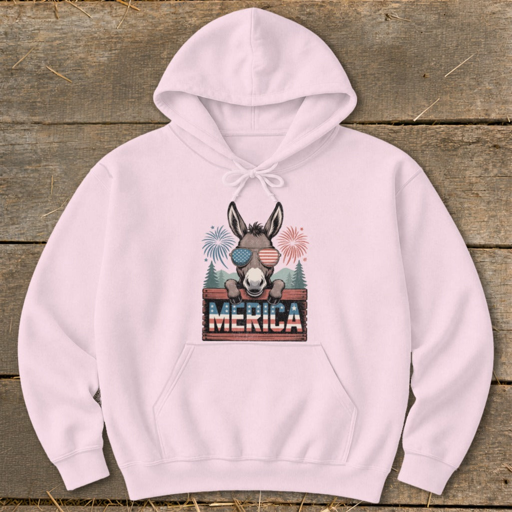 Donkey wearing sunglasses peeks over a sign that says "Merica" with fireworks.