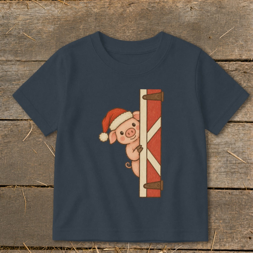 Cute pig wearing a Santa hat peeking from behind a barn door on a t-shirt.