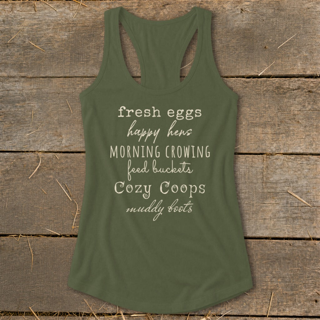 Green tank top with white text: fresh eggs happy hens, morning crowing, feed buckets, cozy coops, muddy boots.