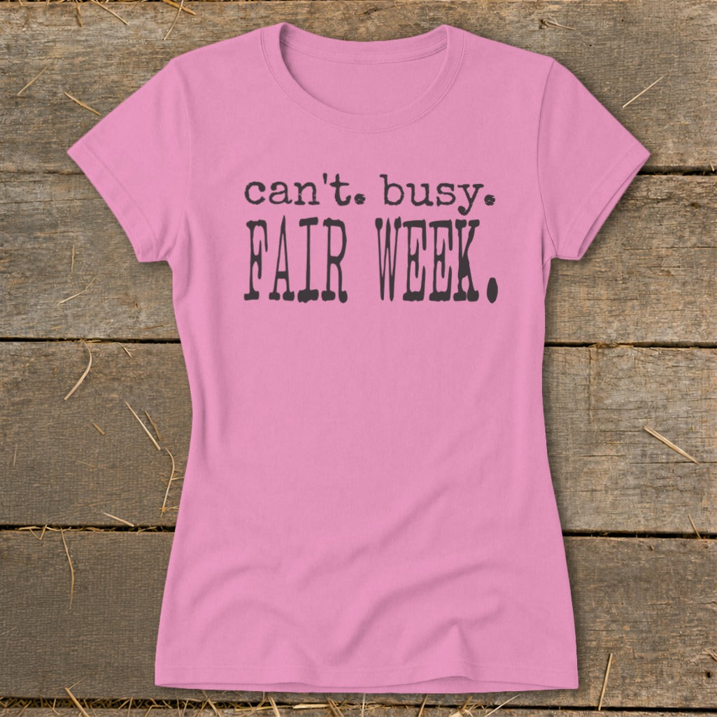Pink t-shirt with "can't. busy. FAIR WEEK." text in dark gray.