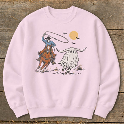 Skeleton cowboy on horse lassoing a ghost cow with longhorns under a yellow moon.