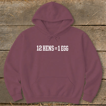 Maroon hooded sweatshirt laid flat on a rustic wooden background, featuring white text reading 12 HENS = 1 EGG.