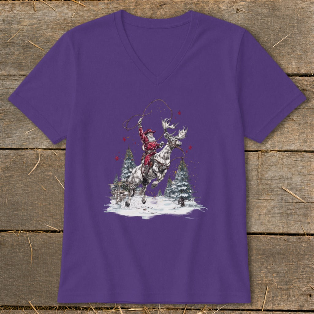Santa riding a reindeer with a lasso in a snowy landscape with trees.
