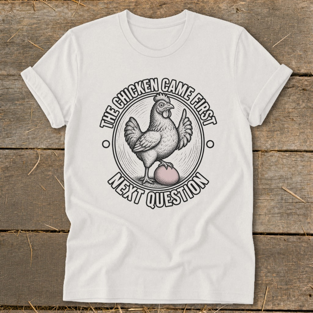 White t-shirt with illustration of a chicken on an egg, text reads "The chicken came first, next question."