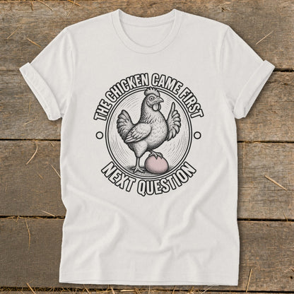 White t-shirt with illustration of a chicken on an egg, text reads "The chicken came first, next question."
