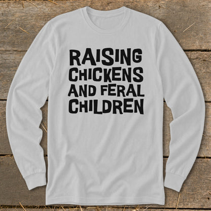 White long-sleeve shirt with black text: Raising Chickens And Feral Children.