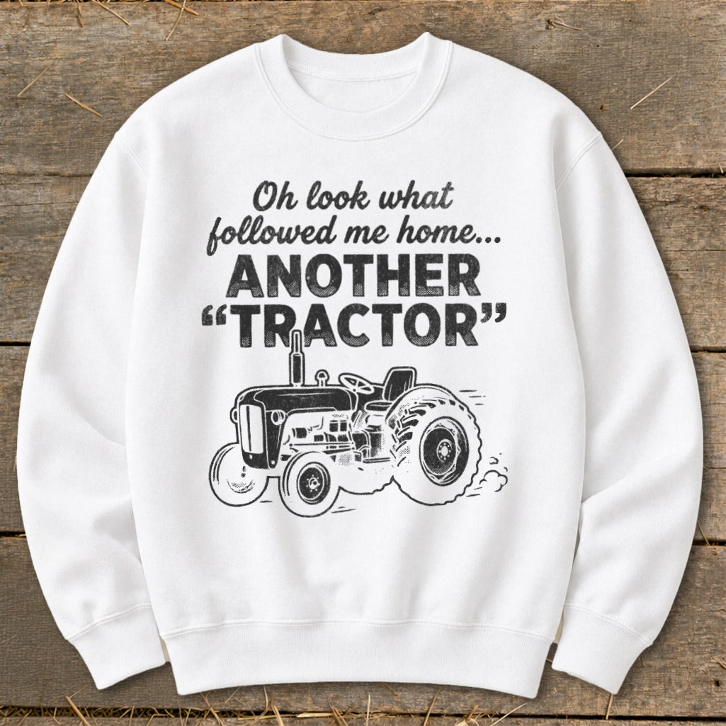 White sweatshirt with text "Oh look what followed me home... ANOTHER TRACTOR" and a tractor graphic.