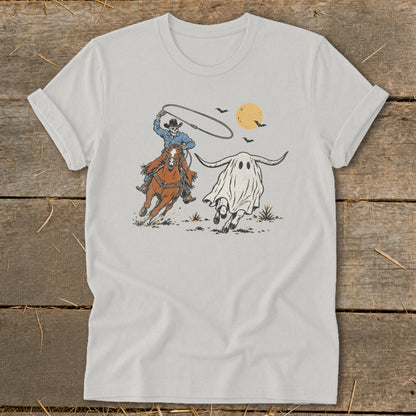 Cowboy skeleton on horse lassos a running ghost with horns under a harvest moon.
