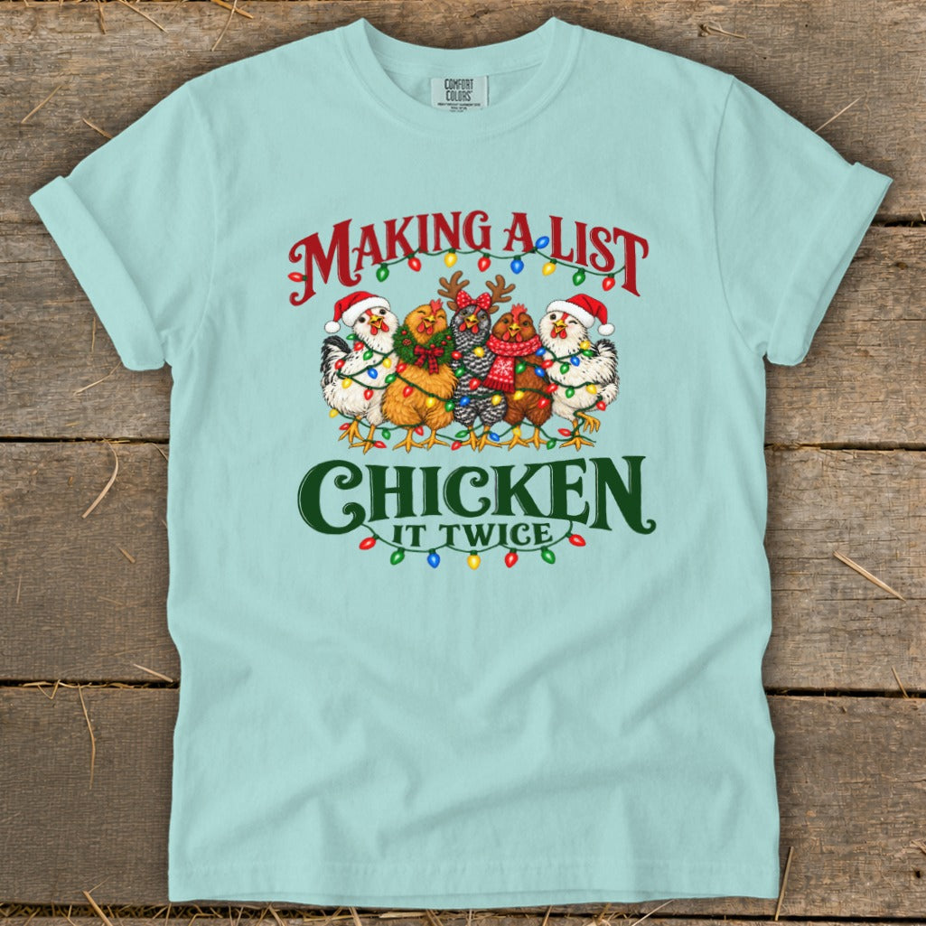 Light blue t-shirt with chickens in Christmas lights, saying "Making a list, Chicken it twice."
