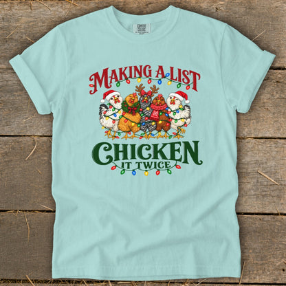 Light blue t-shirt with chickens in Christmas lights, saying "Making a list, Chicken it twice."