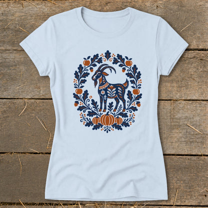 Light blue women's t-shirt featuring a folk art graphic of a goat framed by autumn leaves and pumpkins.