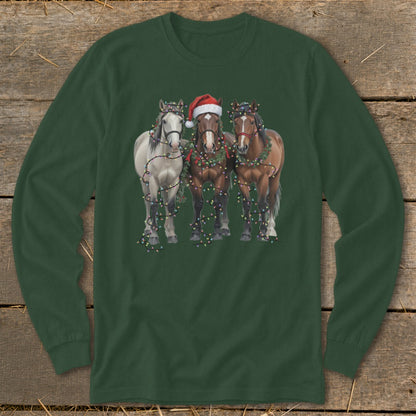 Three horses in festive Christmas lights and garlands, one wearing a Santa hat.
