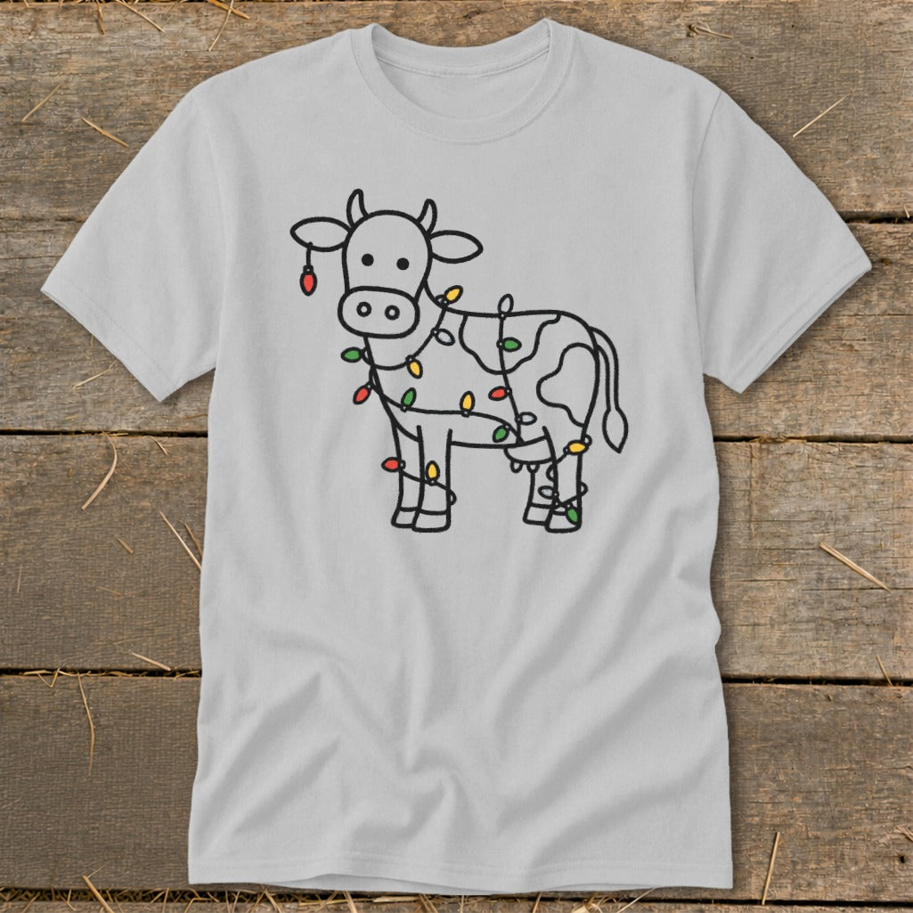 Light grey t-shirt with a black outline drawing of a cow decorated with colorful Christmas lights.