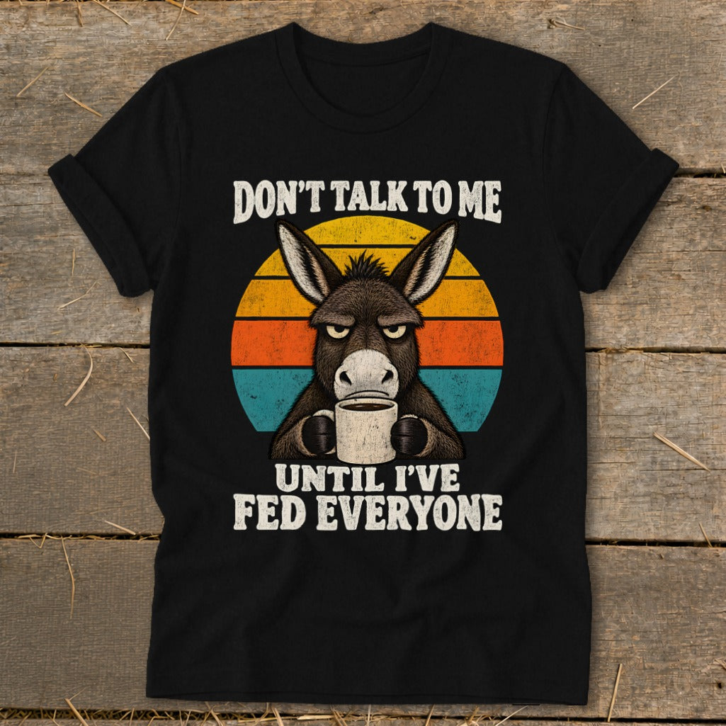 A black t-shirt features a grump donkey drinking coffee, with the text "DON'T TALK TO ME UNTIL I'VE FED EVERYONE."