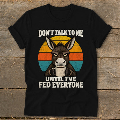 A black t-shirt features a grump donkey drinking coffee, with the text "DON'T TALK TO ME UNTIL I'VE FED EVERYONE."