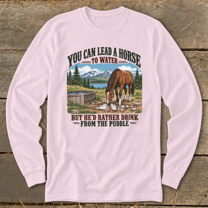 Light pink long-sleeve t-shirt featuring a graphic of a horse drinking from a puddle with text.