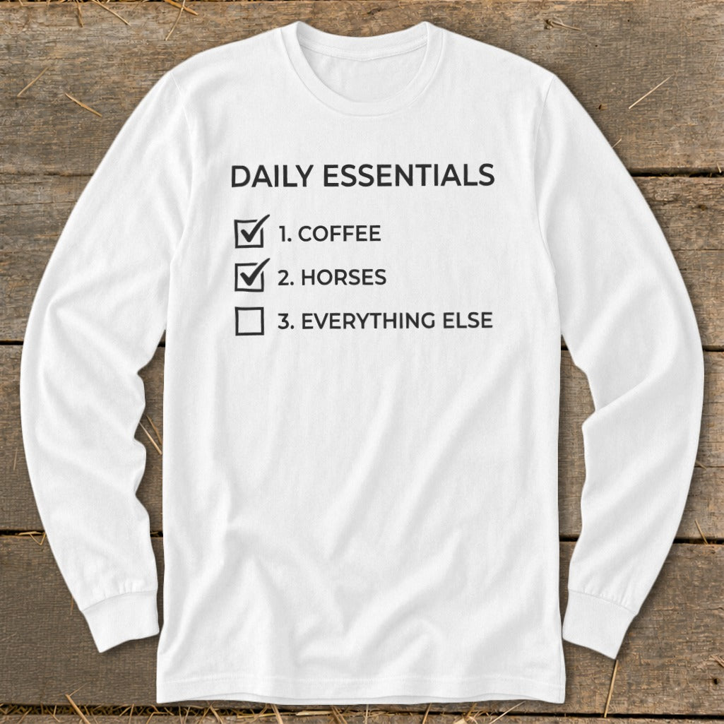 White long sleeve shirt with "Daily Essentials" and a checklist including coffee and horses.