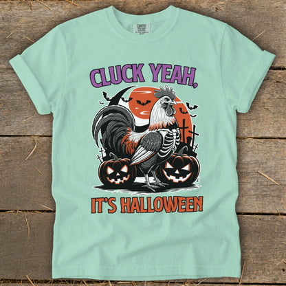 Mint t-shirt with skeleton rooster, pumpkins, and bats, reading "Cluck Yeah, It's Halloween."